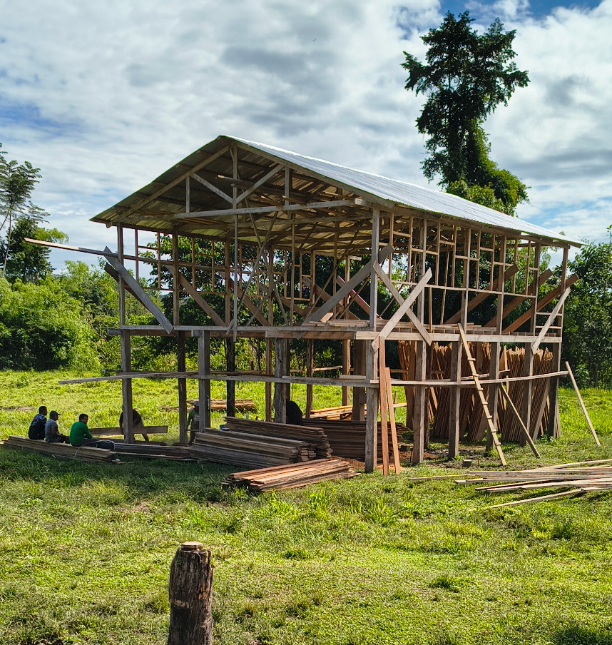 Casa de madeira em construção, com a equipe à sombra
