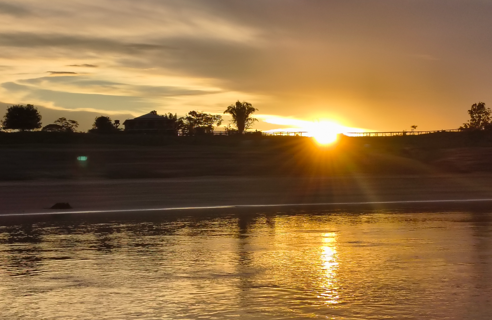 Pôr do sol sobre o rio, com a casa na margem