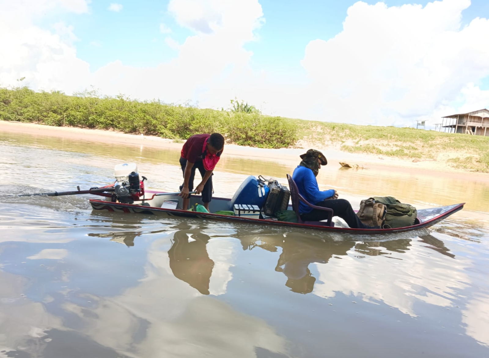 Equipe partindo de canoa a motor pela praia do rio